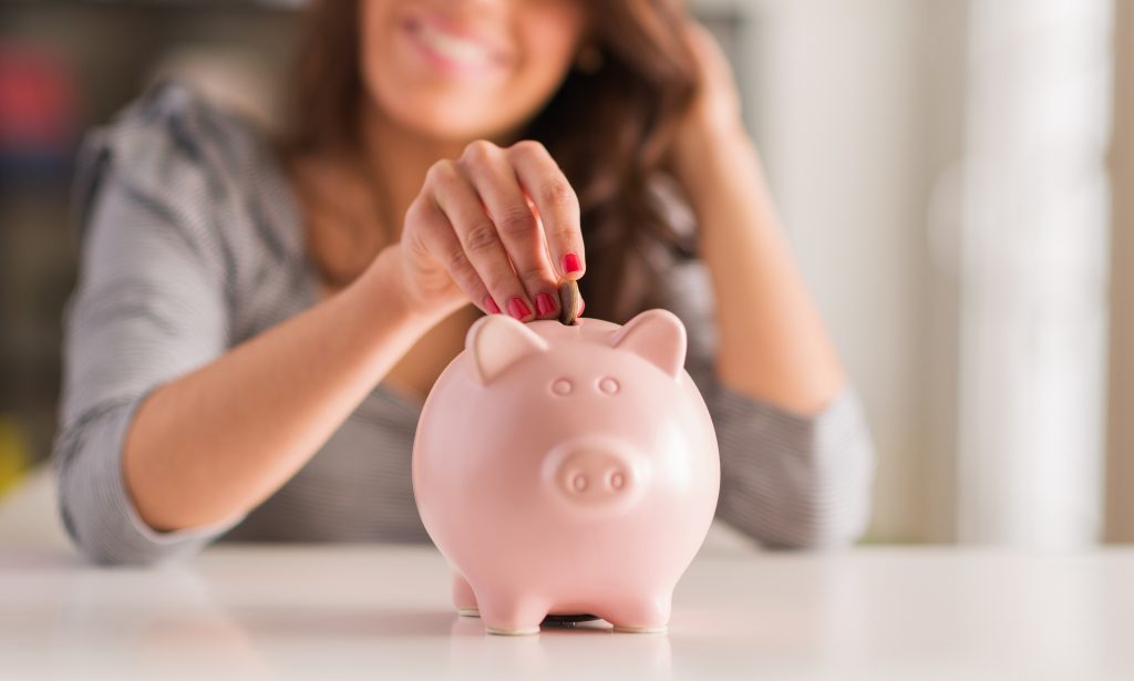 Woman adds money to a piggy bank