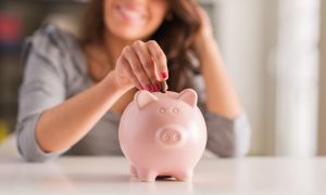 Woman adds money to a piggy bank