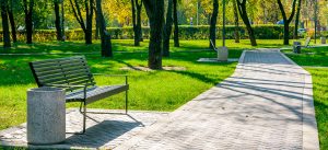 Bench next to a paved pathway in a park